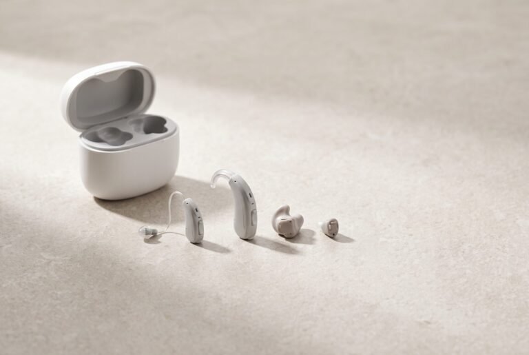 Modern hearing aids and charging case on a stone surface