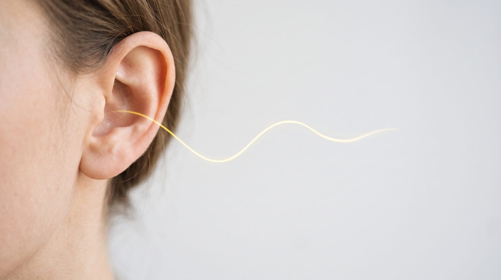 Close-up of an ear with a yellow sound wave